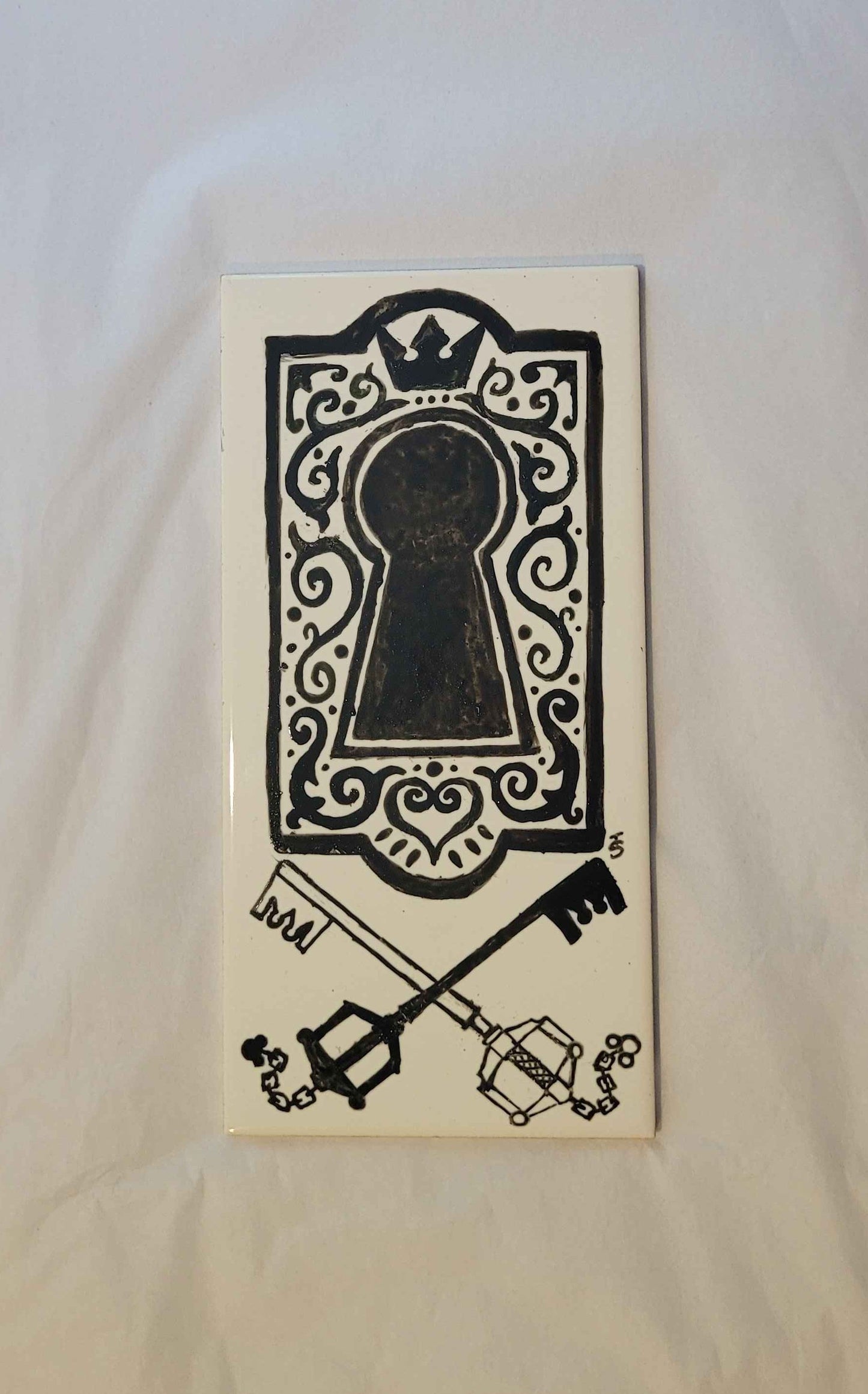 a hand drawn ink art work on a ceramic tile, featuring a decorated key hole and two crossed keyblades from the game kingdom hearts